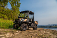 Kubota RTV-X utility vehicle in desert sand with a roof and windshield, by a lake