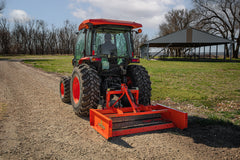Land Pride GS15 series grading scraper on a Kubota tractor with a cab, rear view on a gravel drive