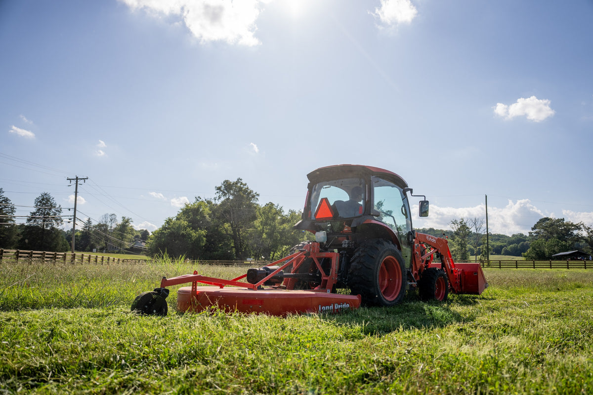 Kubota L3970 ProCab from behind, pulling a rotary cutter through tall grass