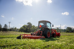 Kubota L3970 ProCab from behind, pulling a rotary cutter through tall grass