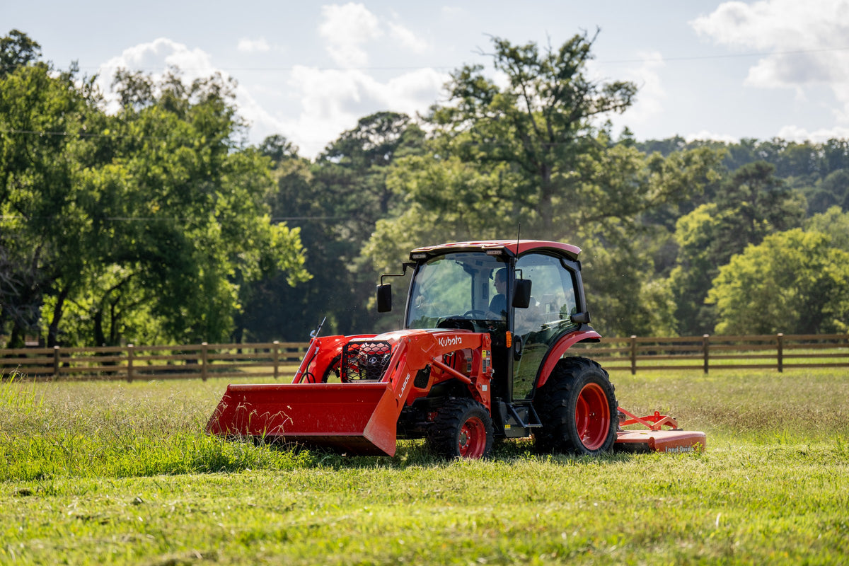 Kubota L3970 ProCab with a front loader, mowing a fenced pasture with a rotary cutter