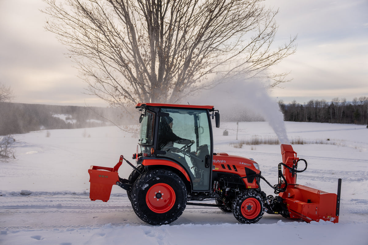 Kubota LX4020 cab tractor with a front snowblower and a WB10 ballast box, clearing snow across an open field