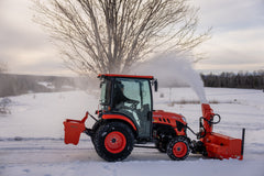 Kubota LX4020 cab tractor with a front snowblower and a WB10 ballast box, clearing snow across an open field
