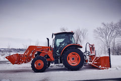 Kubota M4 series cab tractor with a front loader and a rear snowblower, side view on a snowy road
