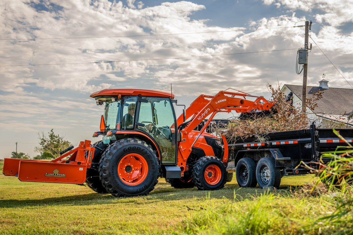 Kubota MX4900 Cab loading brush into a dump trailer with a loader grapple