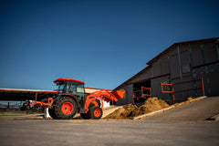 Kubota MX5400 cab tractor with a front loader, parked beside a barn