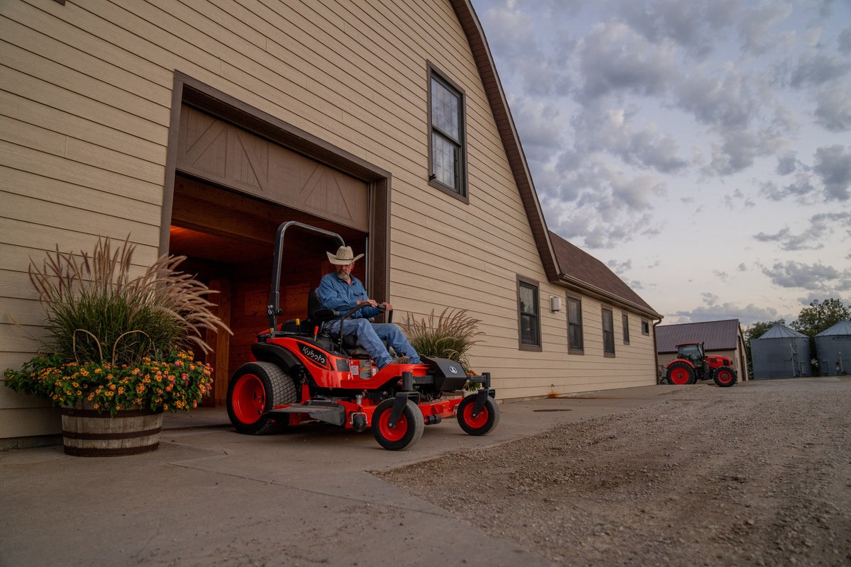 Kubota ZD1211 zero-turn mower at a barn door at dusk