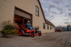 Kubota ZD1211 zero-turn mower at a barn door at dusk
