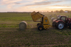 Aerial view of Vermeer 605S Premium round baler ejecting a bale at sunset