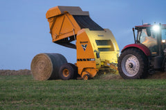 Vermeer 605S Premium round baler ejecting a bale at dusk