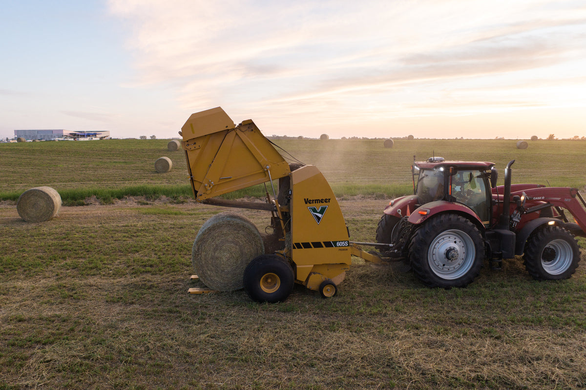 Vermeer 605S Premium round baler ejecting a bale at sunset