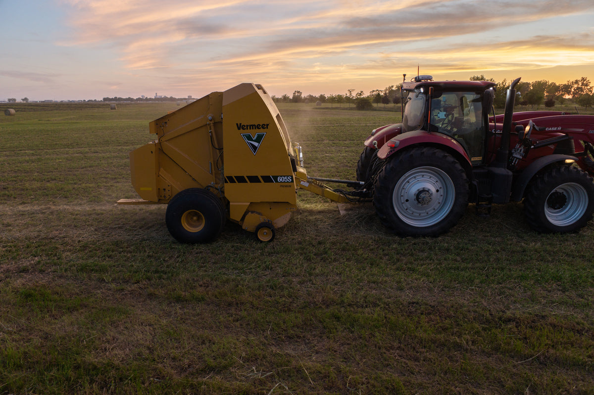 Vermeer 605S Premium round baler baling hay at sunset