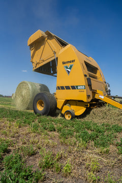 Vermeer 605S Premium round baler tailgate open with bale in the field