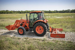 A Kubota tractor with a cab and front loader spreading gravel along a field track with a Land Pride GS25 series grading scraper