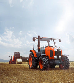 Kubota M6 series cab tractor in a stubble field, a Kubota round baler behind it