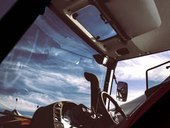 The view from the driver's seat of a Kubota M6 cab tractor: the windshield, roof window and steering wheel