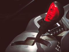 The shift lever and its plus and minus buttons in a Kubota M6 tractor cab, close up