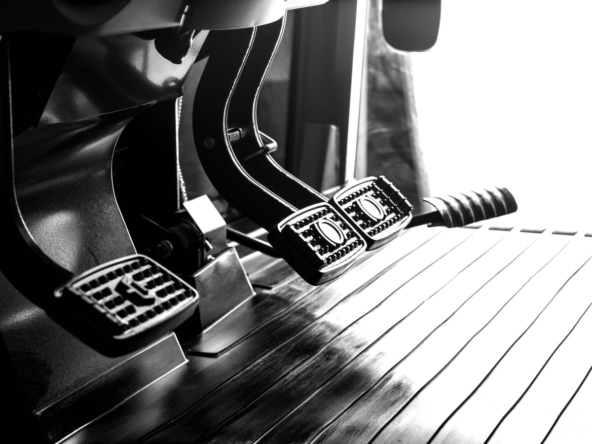 The brake and clutch pedals on the floor of a Kubota M6 tractor cab, close up