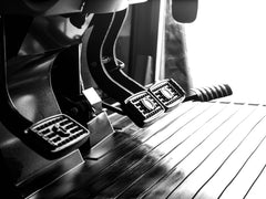The brake and clutch pedals on the floor of a Kubota M6 tractor cab, close up
