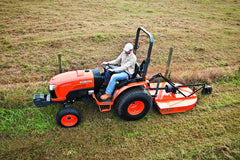 A man mowing tall grass on a slope with a Land Pride RCR1248 rotary cutter behind a Kubota compact tractor