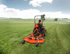 A Land Pride FDR16 series grooming mower leaving a striped lawn behind a Kubota compact tractor, seen from behind
