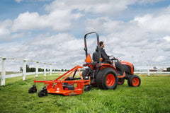 A man mowing beside a white fence with a Land Pride FDR16 series grooming mower behind a Kubota compact tractor