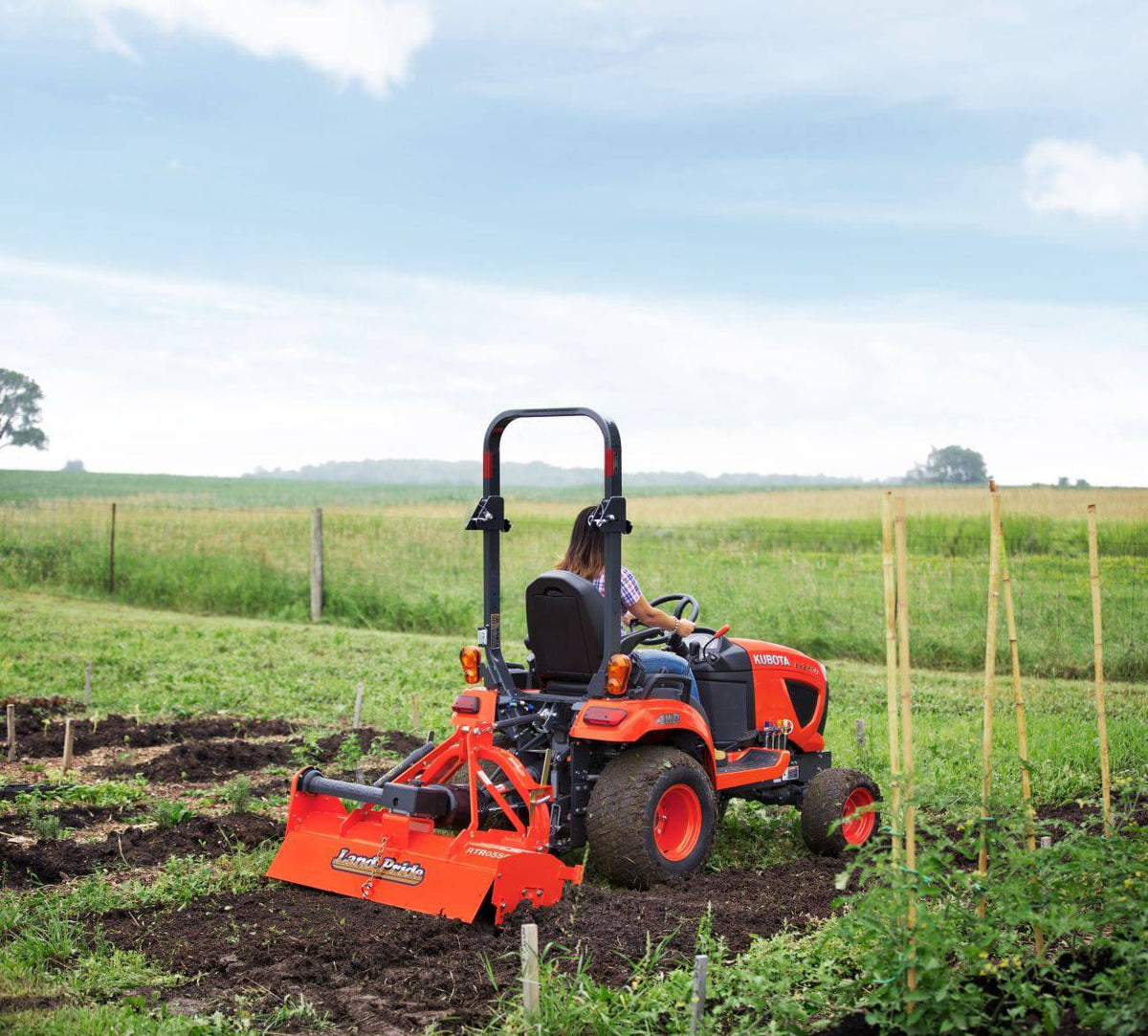 A woman tilling a vegetable garden with a Land Pride RTR05 series rotary tiller on a Kubota sub-compact tractor
