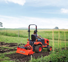 A woman tilling a vegetable garden with a Land Pride RTR05 series rotary tiller on a Kubota sub-compact tractor