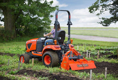 Land Pride RTR05 series rotary tiller on a Kubota sub-compact tractor in a vegetable garden, rear three-quarter view