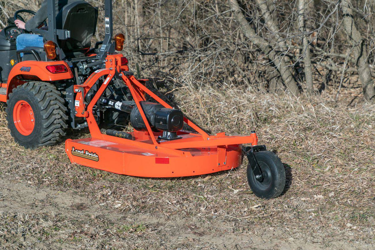 Land Pride RCR12 series rotary cutter on a Kubota sub-compact tractor, cutting dry brush at the edge of a wood