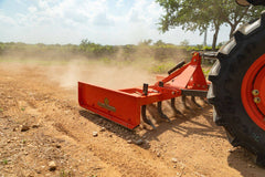 A Land Pride GS25 series grading scraper raising dust on dry ground behind a Kubota tractor
