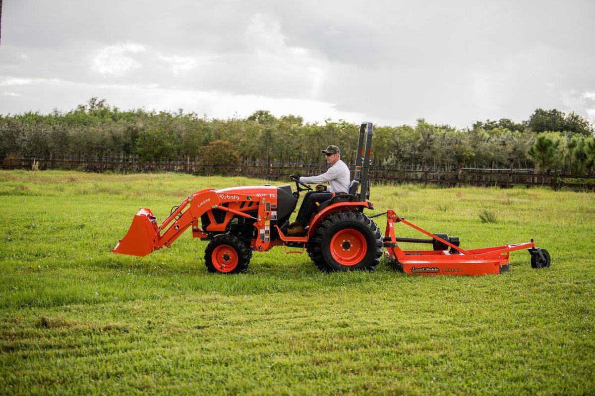 Kubota compact tractor with a front loader pulling a Land Pride RCR1260 rotary cutter across a mown field