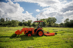 A man mowing a pasture with a Land Pride RCR12 series rotary cutter behind a Kubota compact tractor with a canopy and front loader